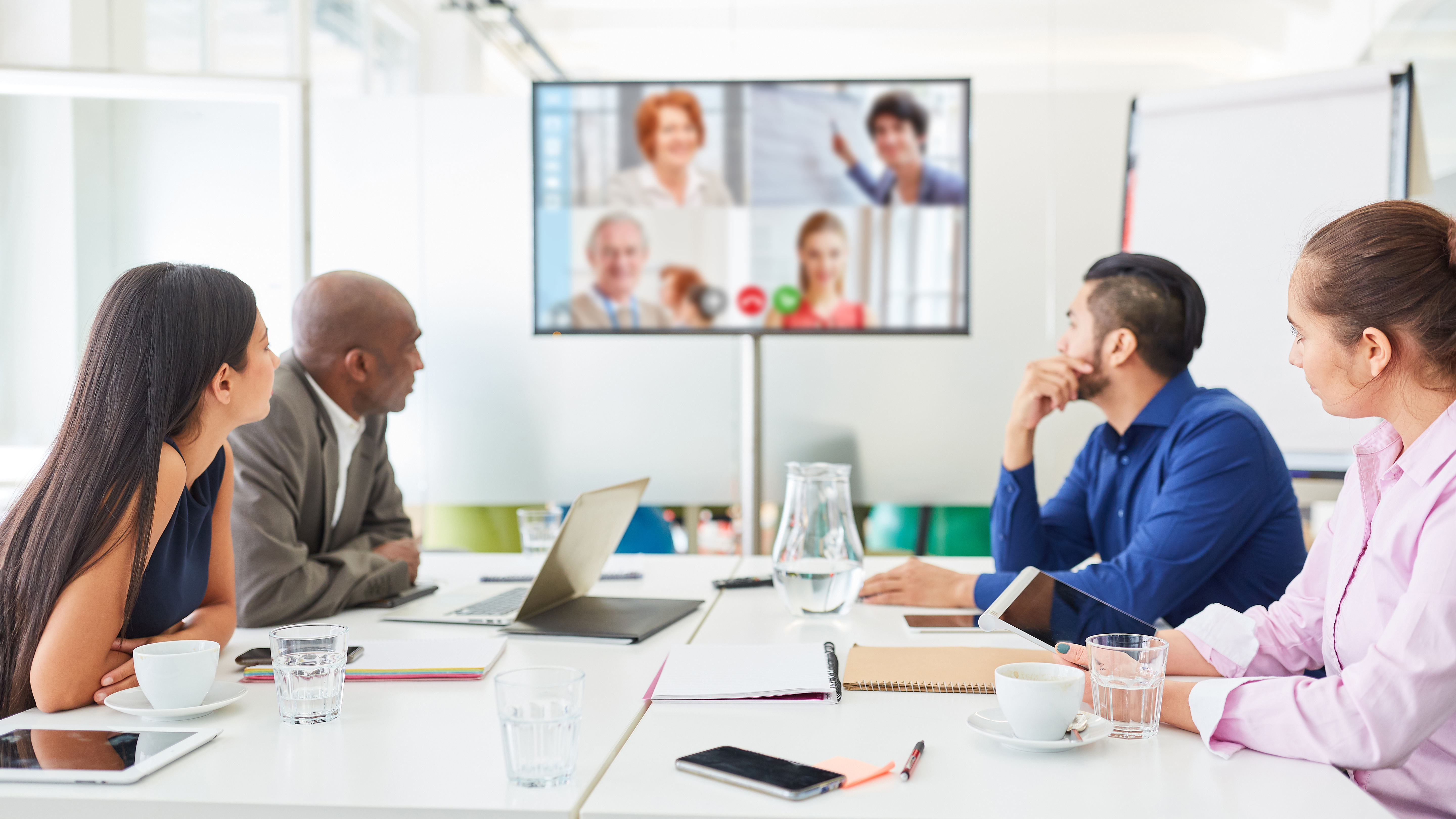 Digital video conference on monitor at business team meeting in conference room
